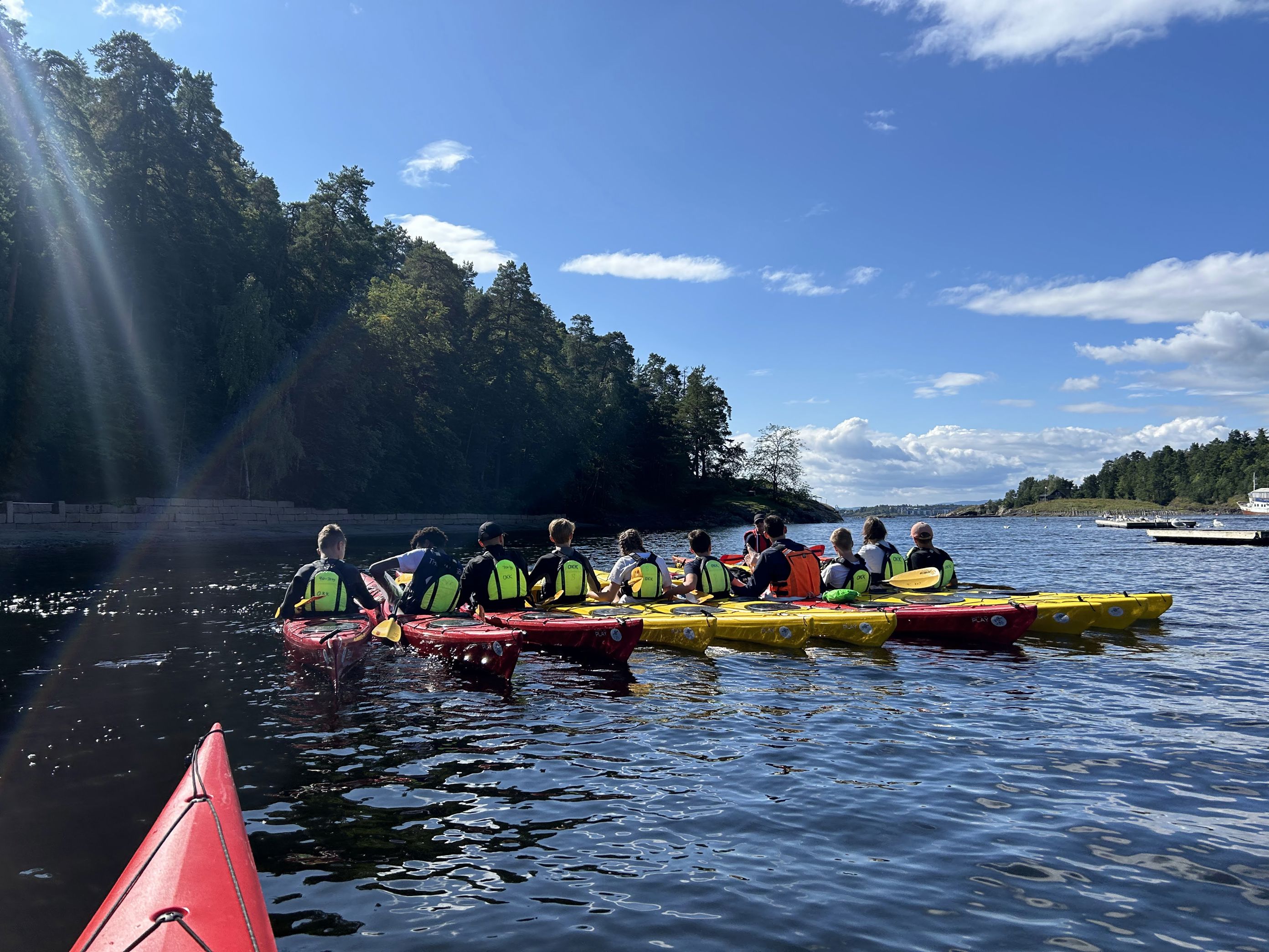 En gruppe mennesker i kanoer på en elv En gruppe mennesker i kanoer på en elv