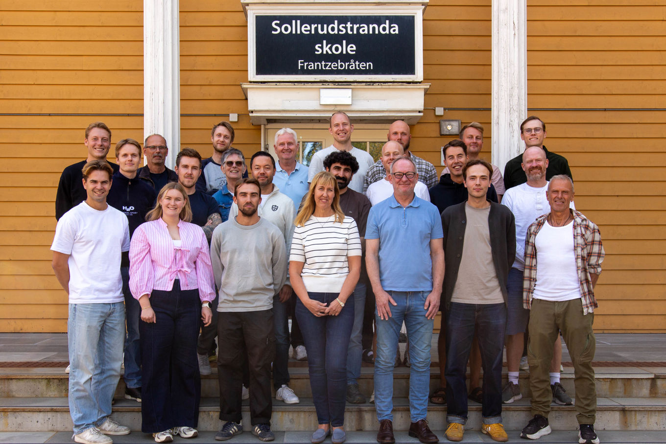 en gruppe mennesker som poserer for et bilde foran en bygning